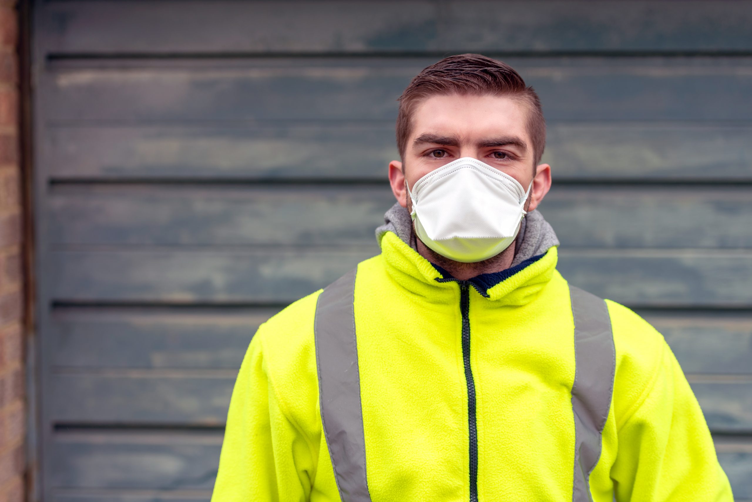 Virus mask Causasian man wearing face protection in prevention for coronavirus. Isolated male looking into the camera in yellow jacket